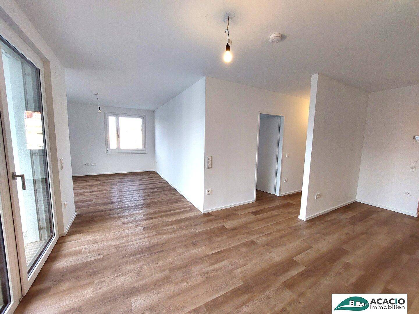 Heller Wohnbereich mit großen Fenstern und modernem Laminatboden, bereit zum Einzug.