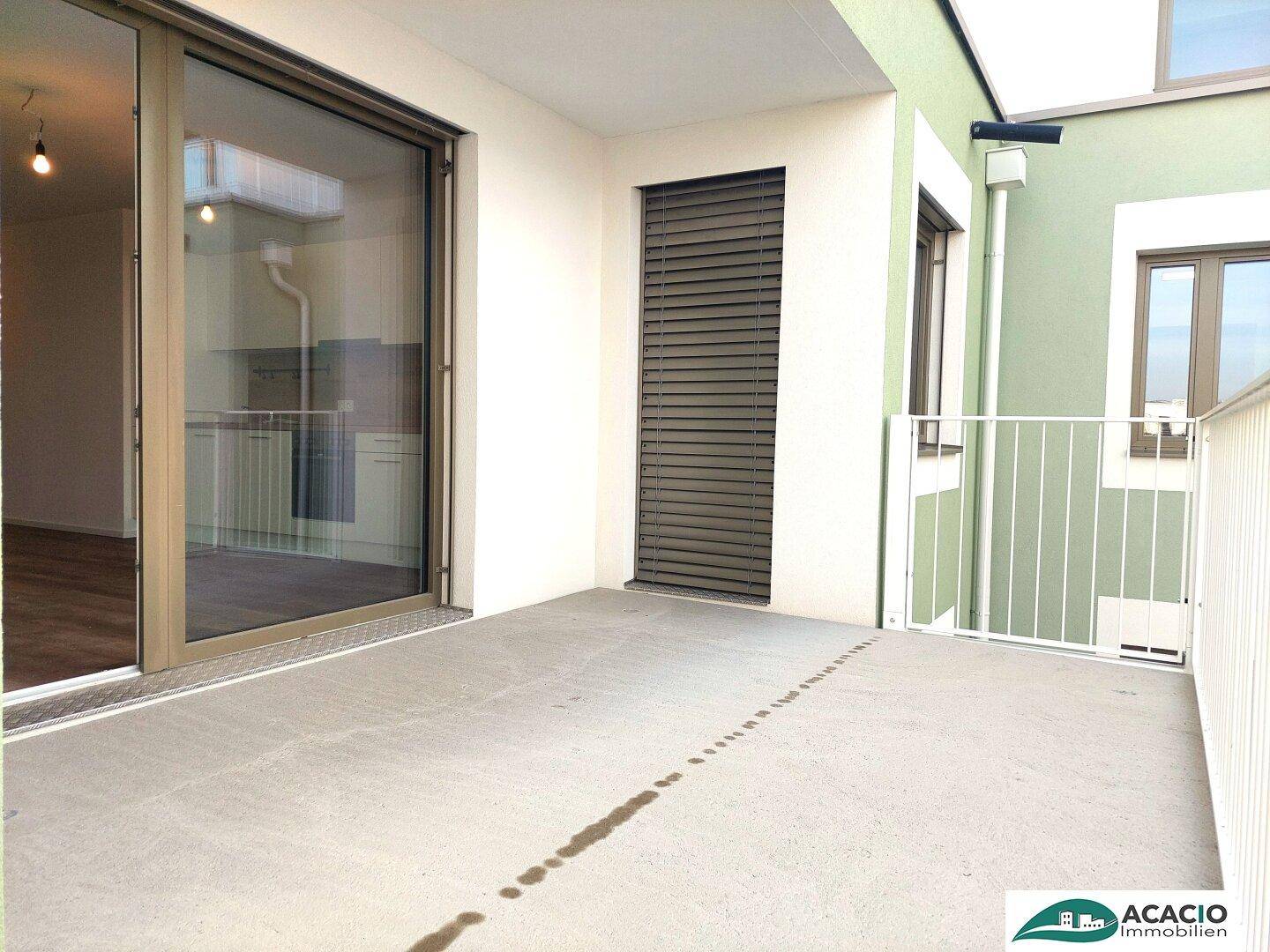 Geräumiger Balkon mit Betonboden und Blick auf die umliegenden Gebäude.