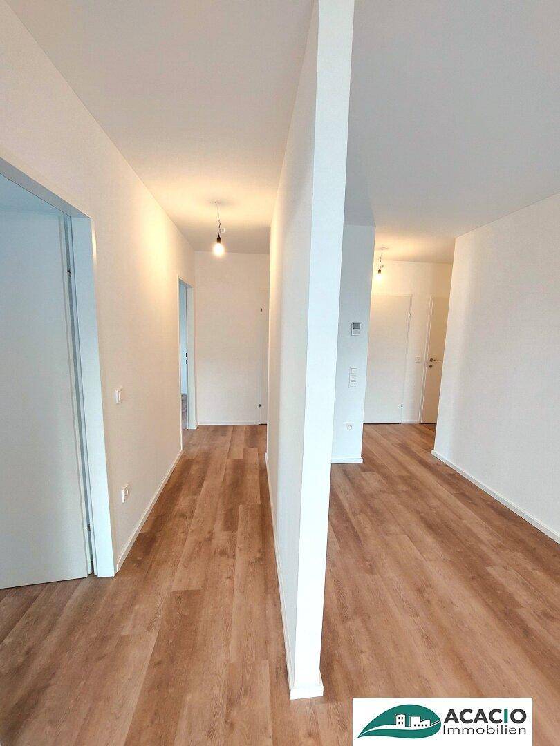 Langer, heller Flur mit modernem Laminatboden und Zugang zu mehreren Zimmern.