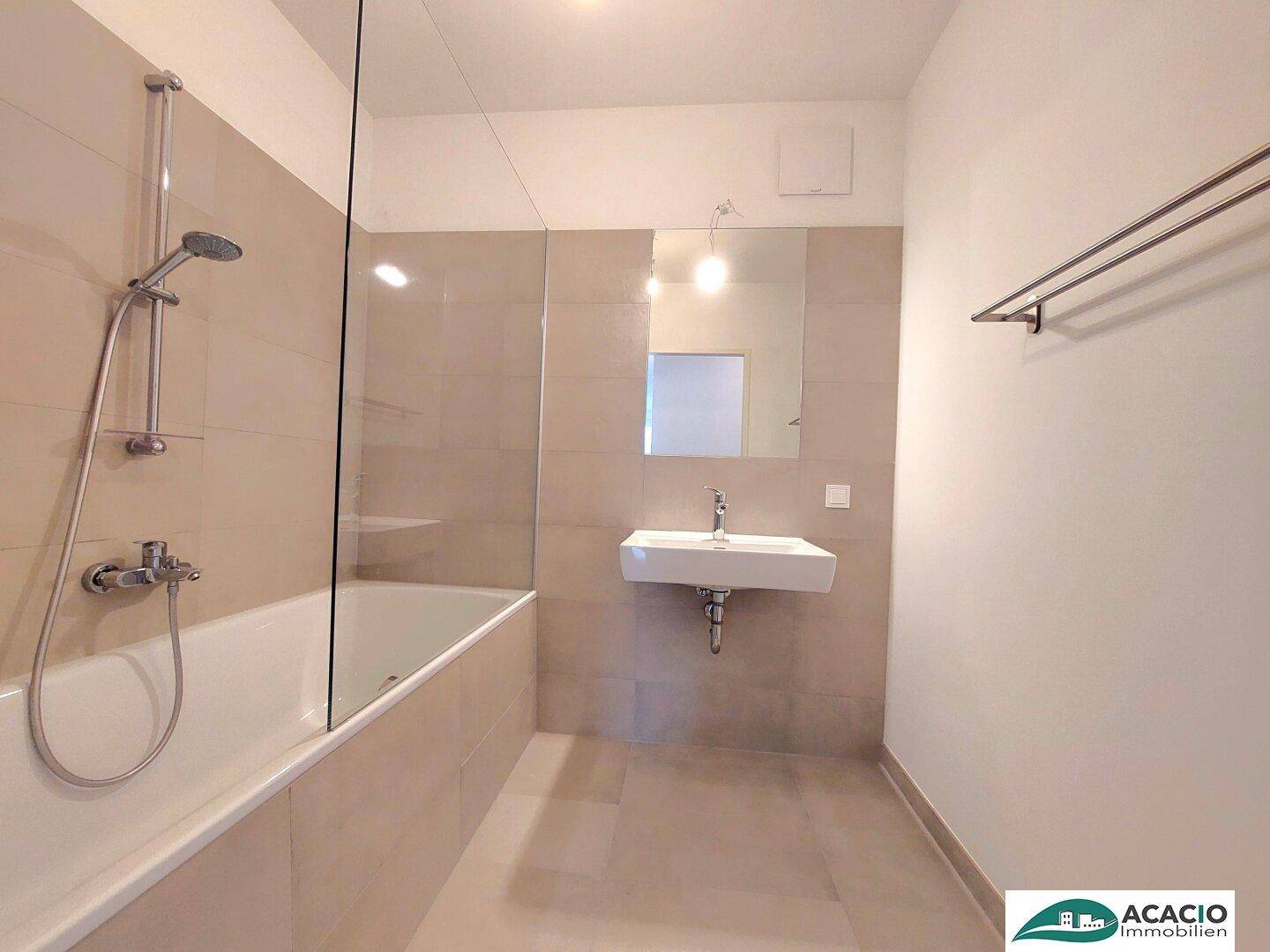 Modernes Badezimmer mit Badewanne, Einzelwaschbecken und hellen Fliesen.