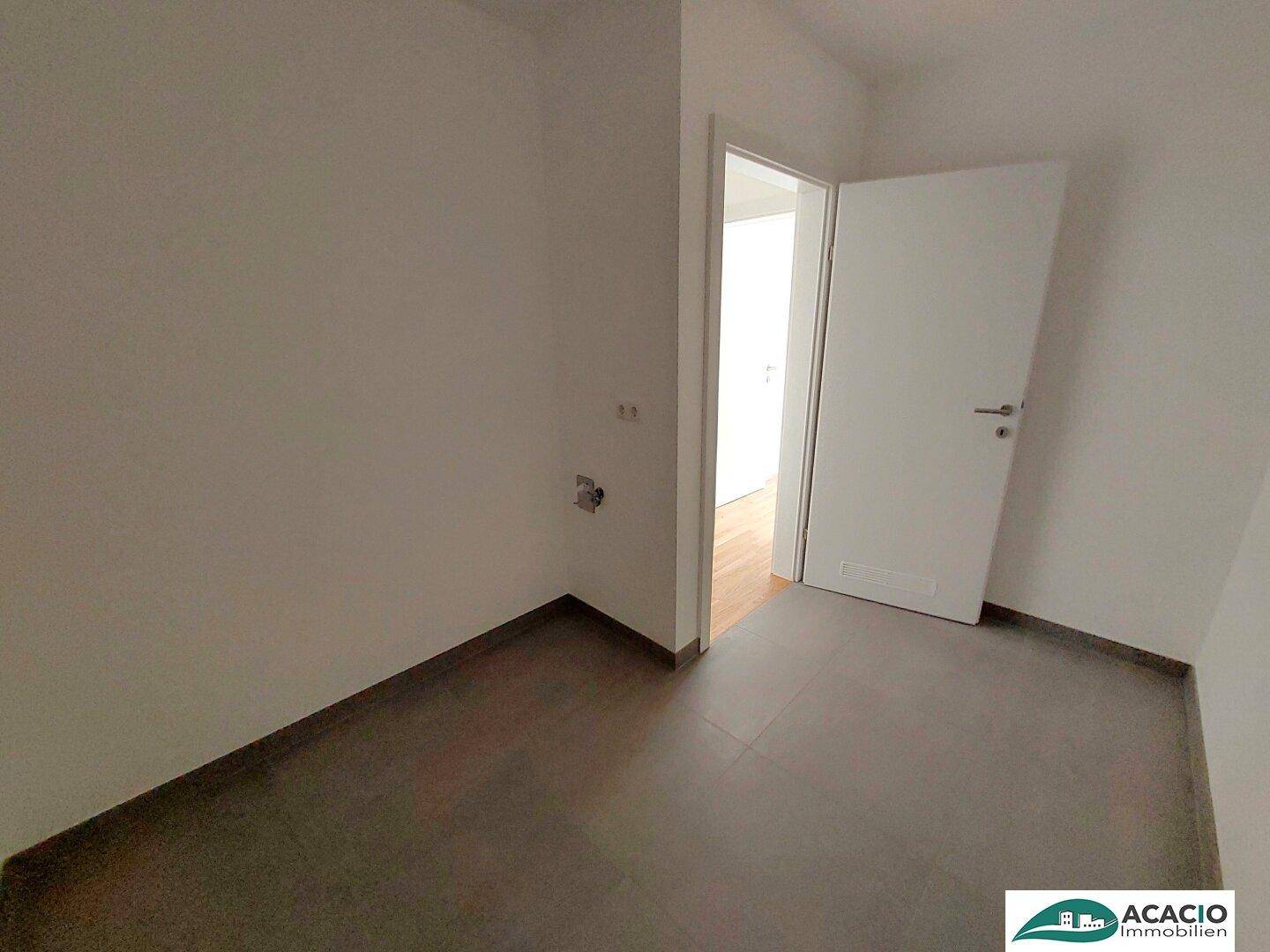 Praktischer Hauswirtschaftsraum mit Fliesenboden und Anschlüssen für Geräte.