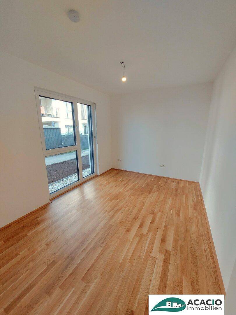 Helles Zimmer mit Parkettboden und großer Fensterfront, ideal als Schlafzimmer oder Büro.