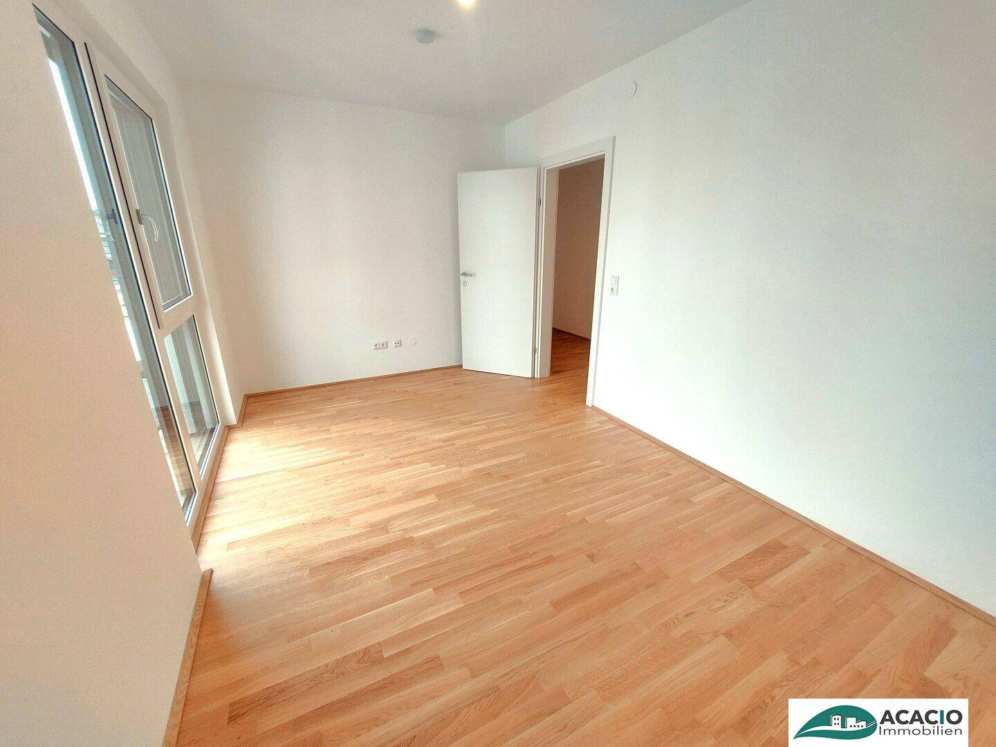 Lichtdurchfluteter Raum mit Parkettboden und Zugang zu einem weiteren Zimmer, ideal für flexible Nutzung.