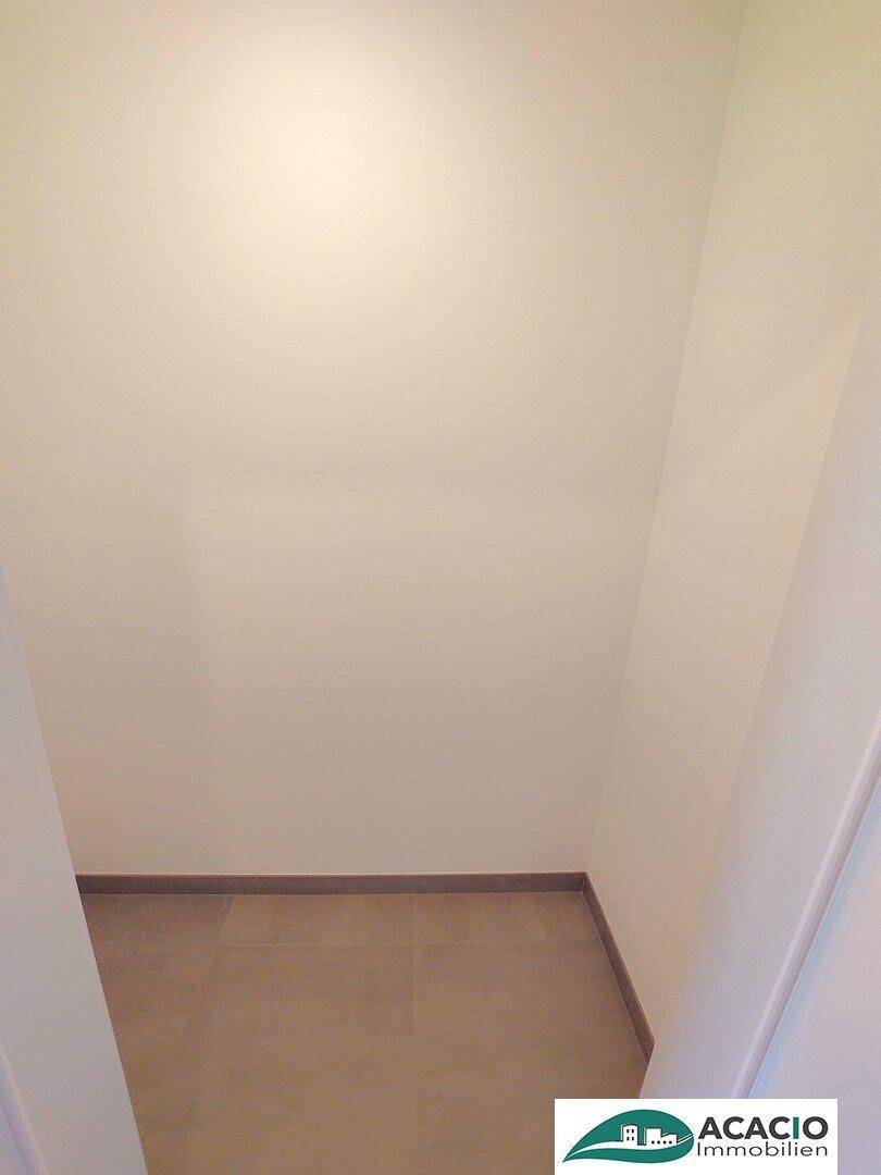 Schmaler Flur mit hellen Wänden und Fliesenboden, der zu weiteren Räumen führt.