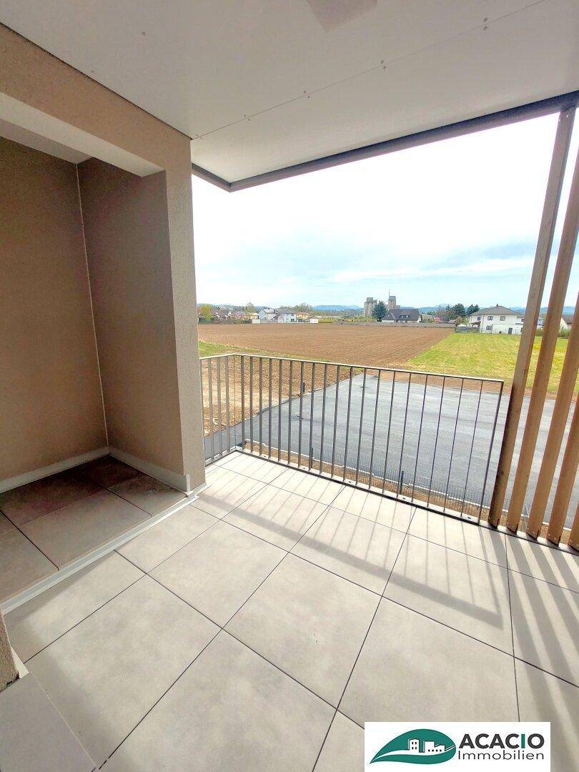 Geräumiger Balkon mit Fliesenboden und weitem Blick über Felder und die Umgebung.