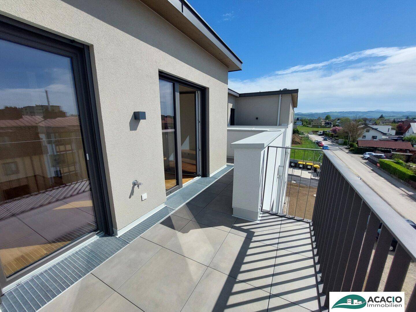 Geräumiger Balkon mit Fliesenboden und Metallgeländer, bietet einen weiten Blick auf die Umgebung.