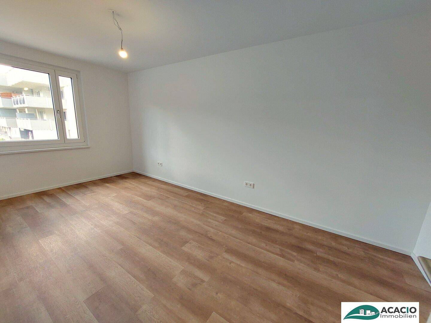Ruhiges Zimmer mit Holzboden und einem Fenster, ideal als Schlafzimmer oder Arbeitszimmer nutzbar.