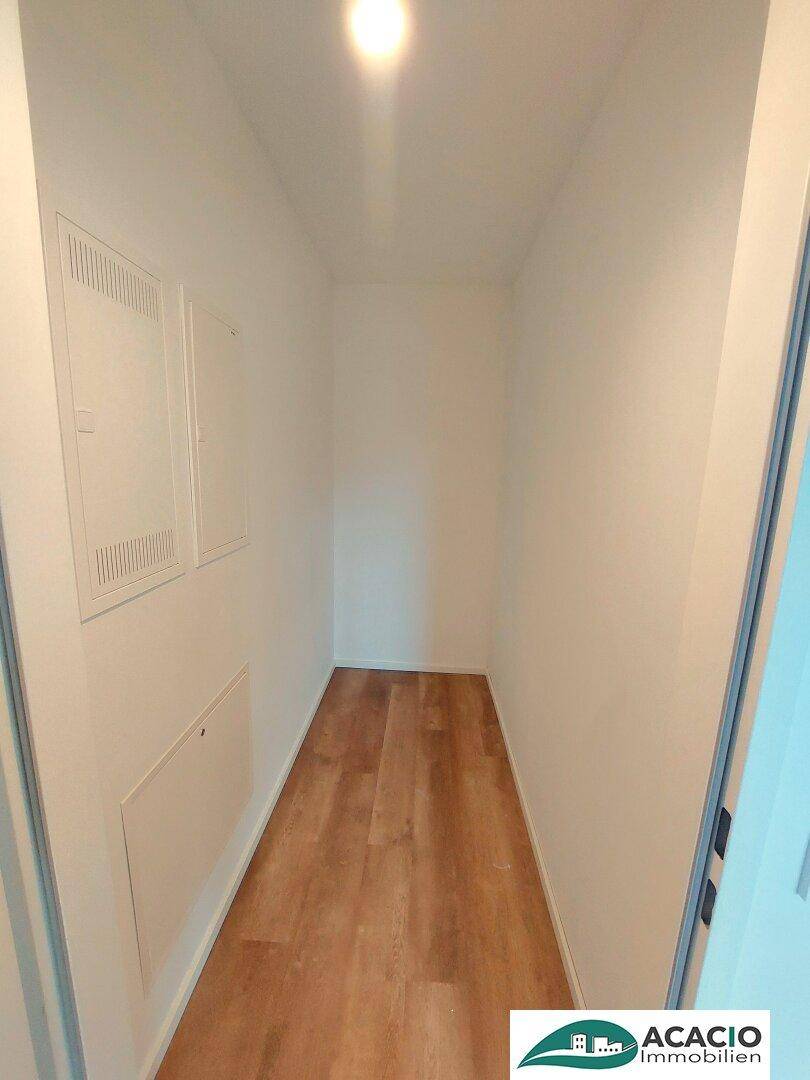 Praktischer Abstellraum mit Holzboden und weißen Wänden, ideal für Haushaltsgeräte und Lagerung.