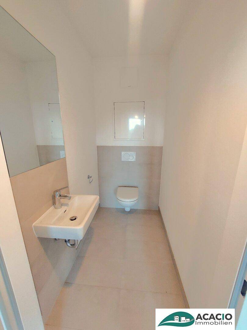 Kompaktes Gäste-WC mit wandhängender Toilette und kleinem Waschbecken, in modernem Design.