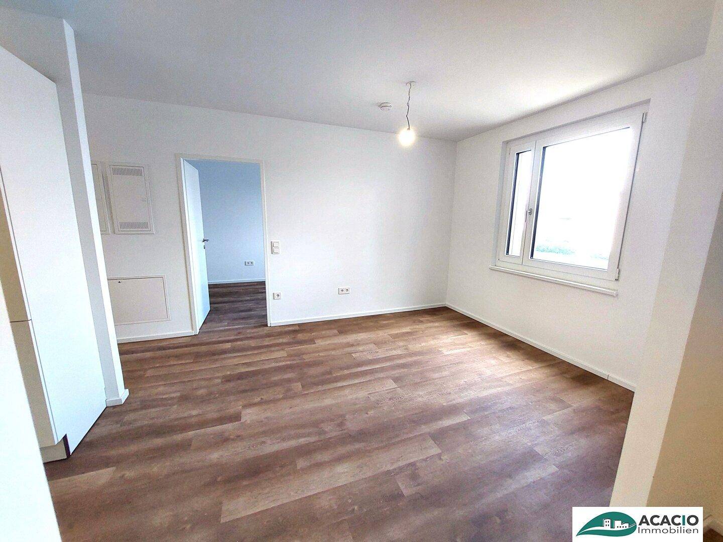 Helles Zimmer mit Laminatboden und großem Fenster, ideal als Schlaf- oder Arbeitszimmer.