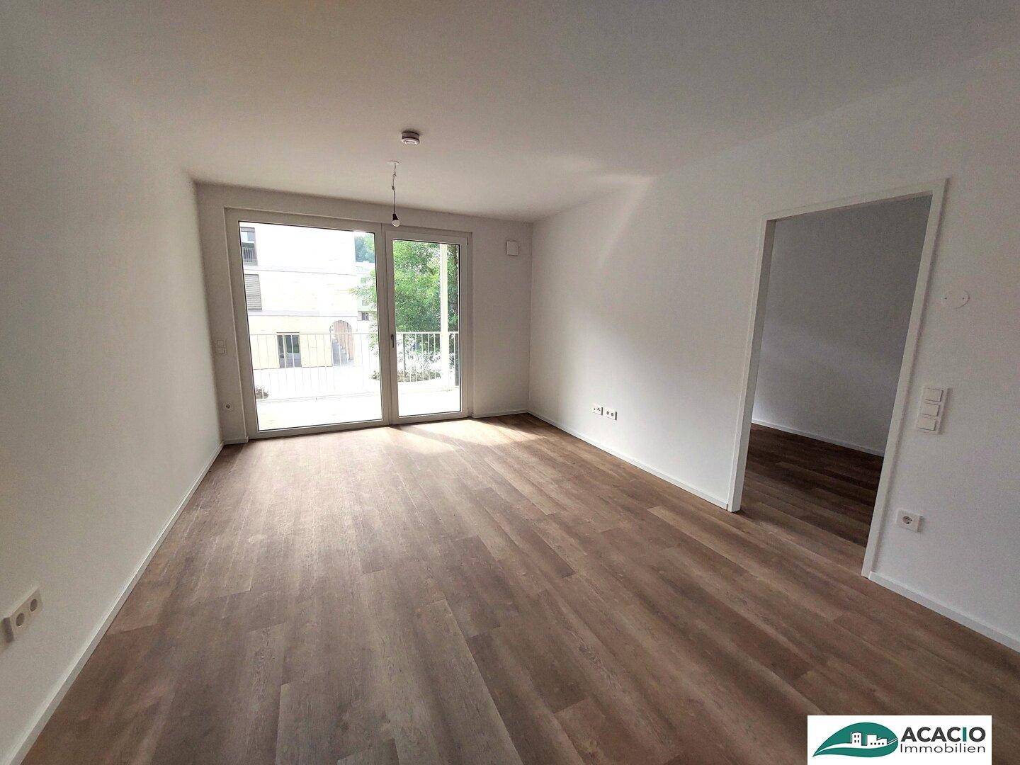Lichtdurchfluteter Raum mit Laminatboden und breitem Zugang zum Balkon.