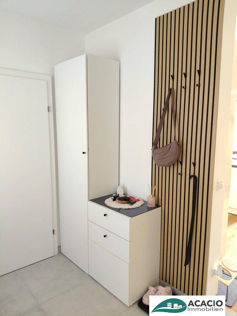 Heller Flurbereich mit modernem Garderobenschrank und dekorativer Holzlamellenwand.