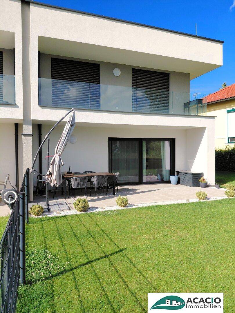 Gepflegter Gartenbereich mit Rasenfläche und einer Terrasse vor der modernen Doppelhaushälfte.