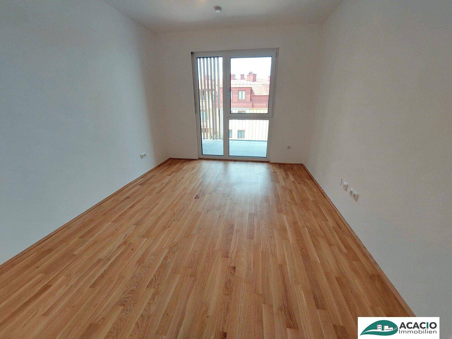 Geräumiges Schlafzimmer mit Holzboden und großem Fenster, das einen Blick auf die Umgebung bietet.