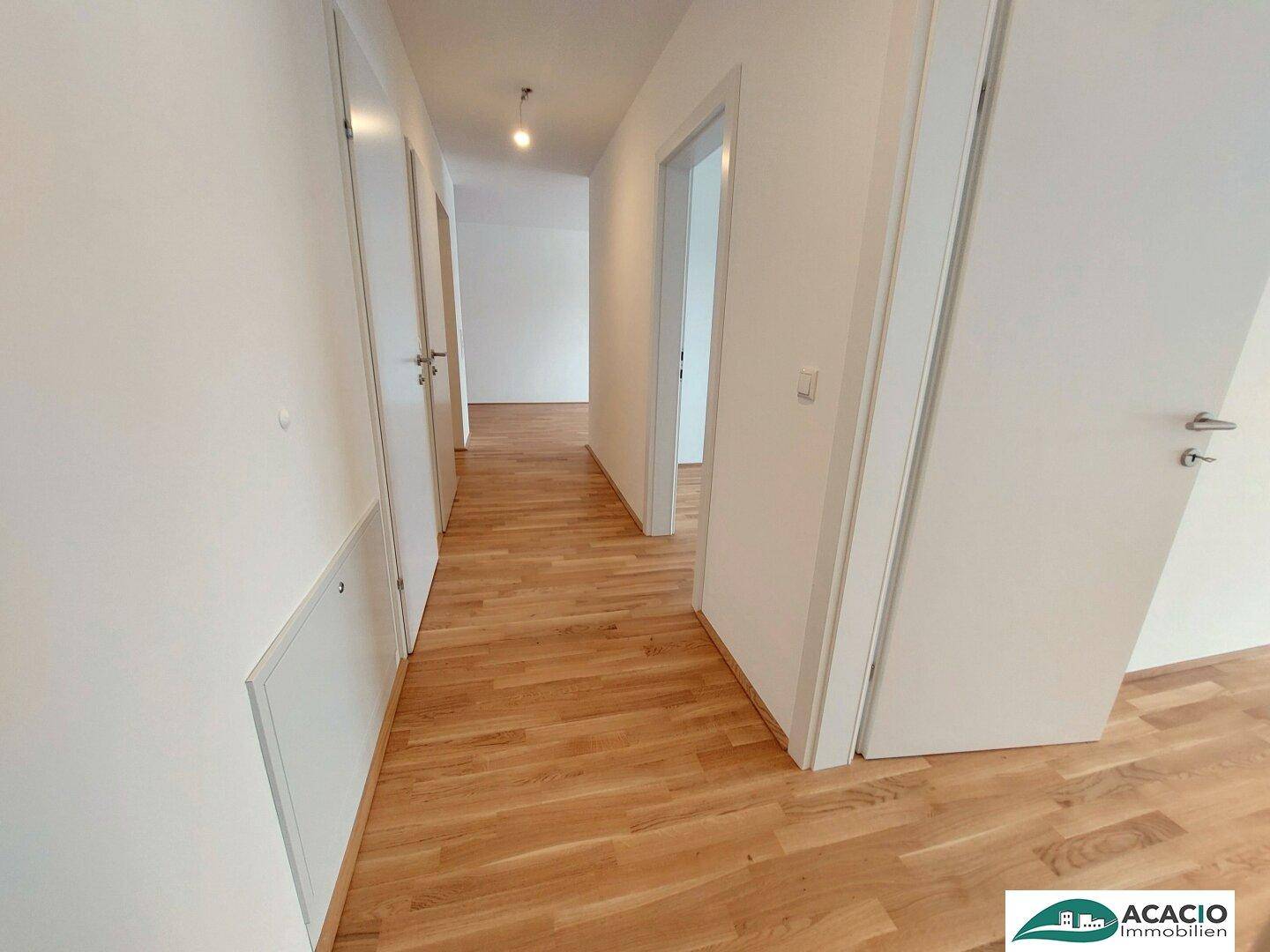 Heller Flur mit Holzboden und mehreren weißen Türen, der zu verschiedenen Räumen führt.