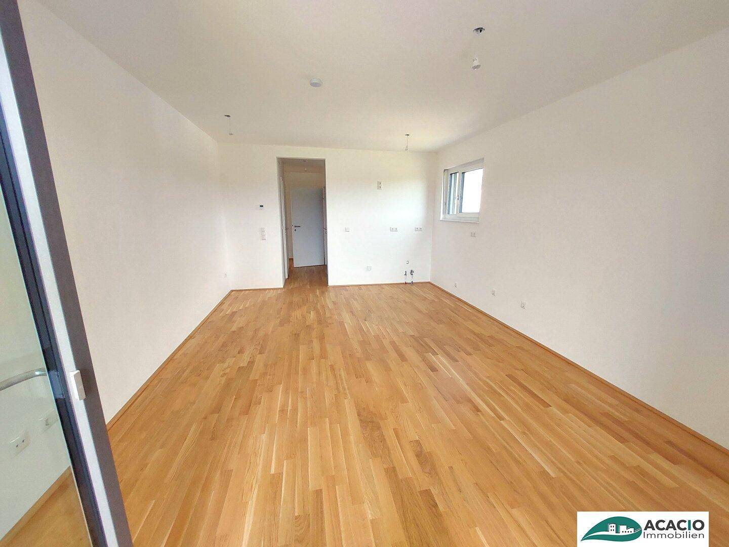 Geräumiges, leeres Zimmer mit hellem Parkettboden und einem Fenster, bereit zur individuellen Gestaltung.