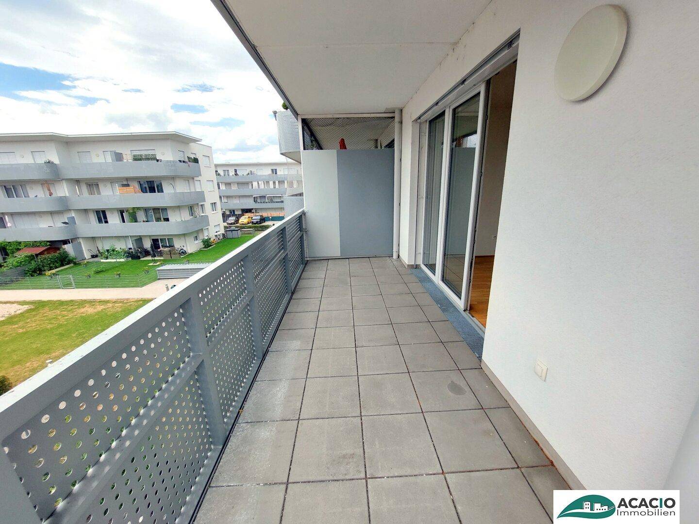 Geräumiger Balkon mit Fliesenboden und moderner Metallbrüstung, bietet Ausblick auf die Umgebung.