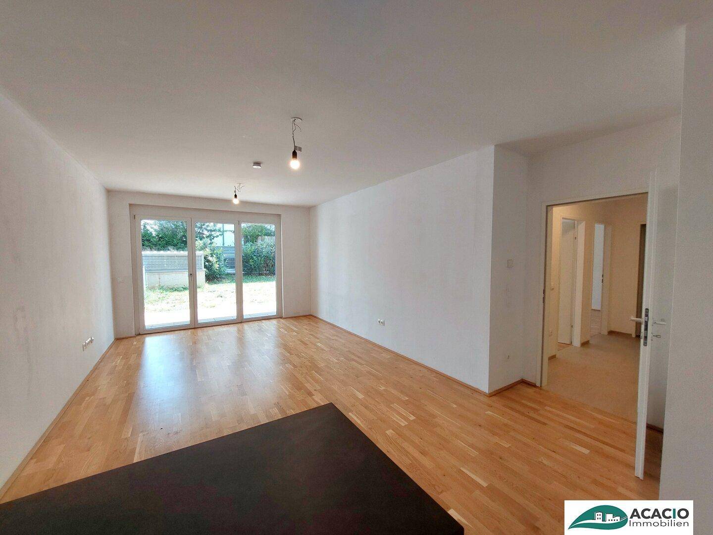 Geräumiges Wohnzimmer mit Parkettboden und großen Fenstertüren zum Garten.