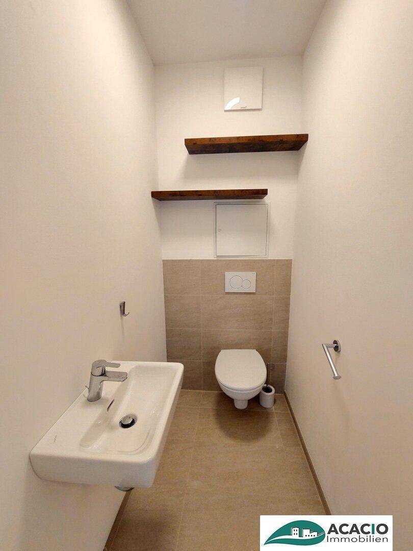 Separates Gäste-WC mit modernem Waschbecken, Wand-WC und Fliesenboden.