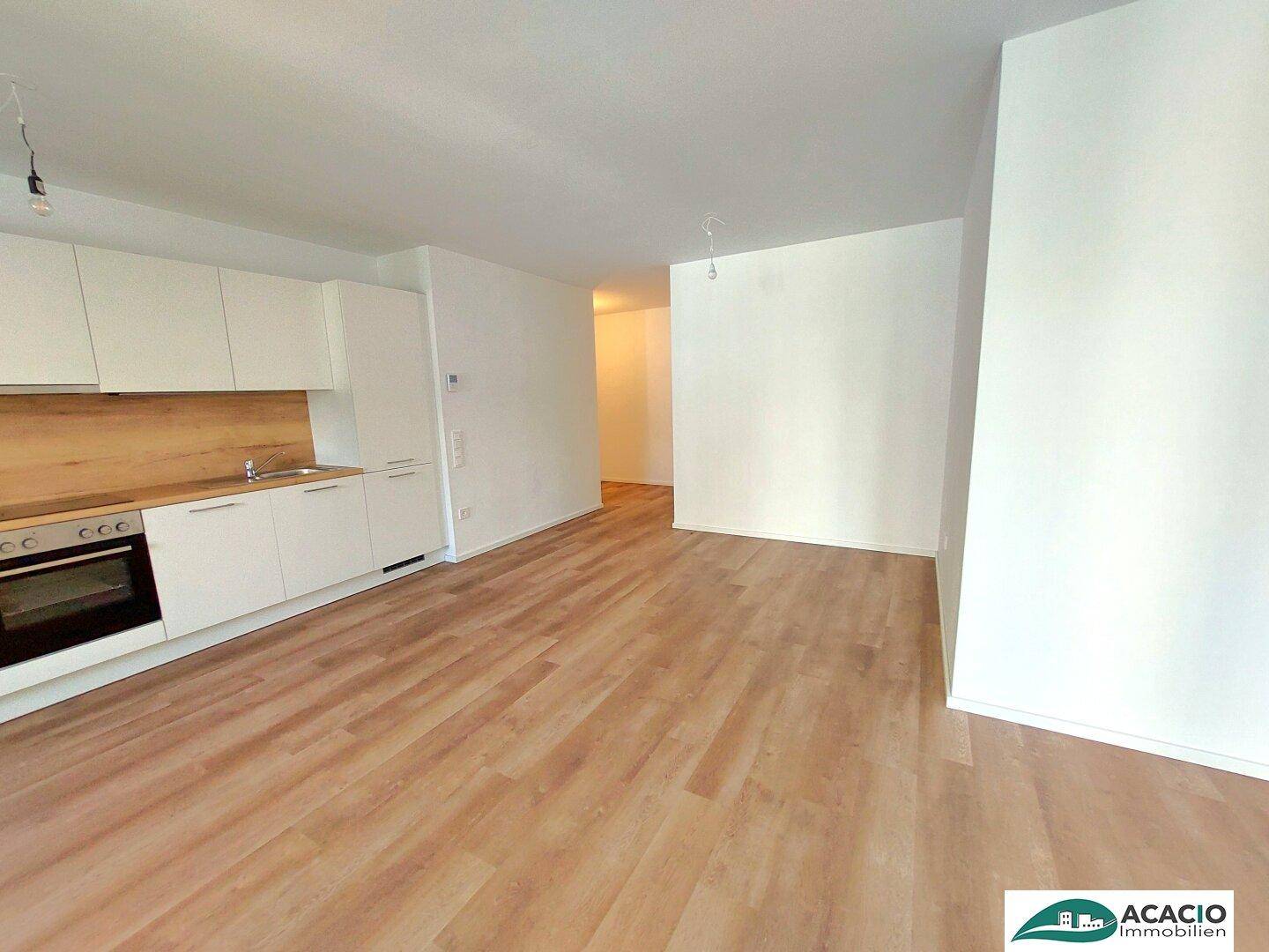 Geräumiger Wohnbereich mit heller Küchenzeile und durchgehendem Laminatboden, bereit zum Einzug.