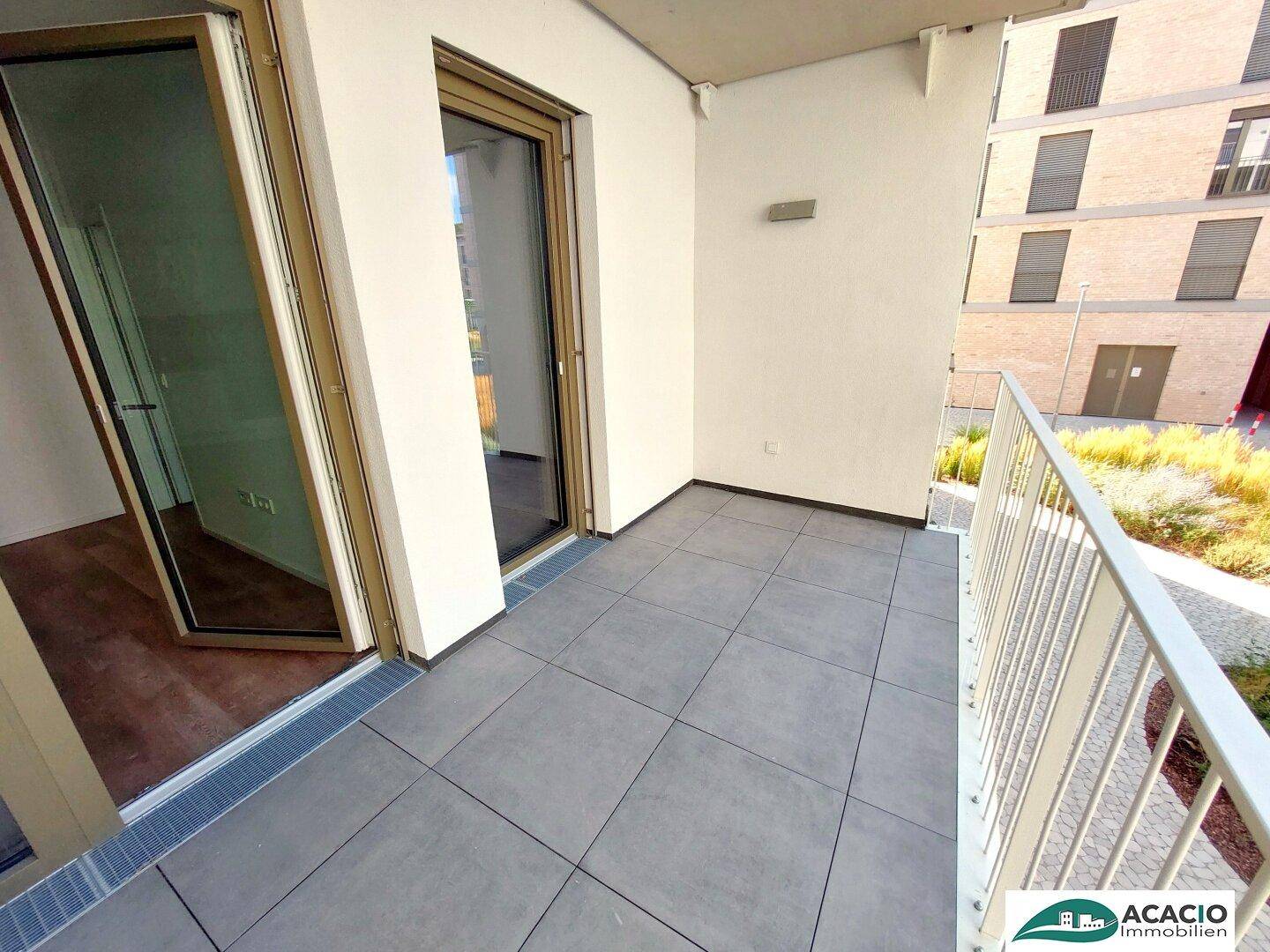 Geräumiger Balkon mit modernen Fliesen und direktem Zugang zum Innenbereich der Wohnung.