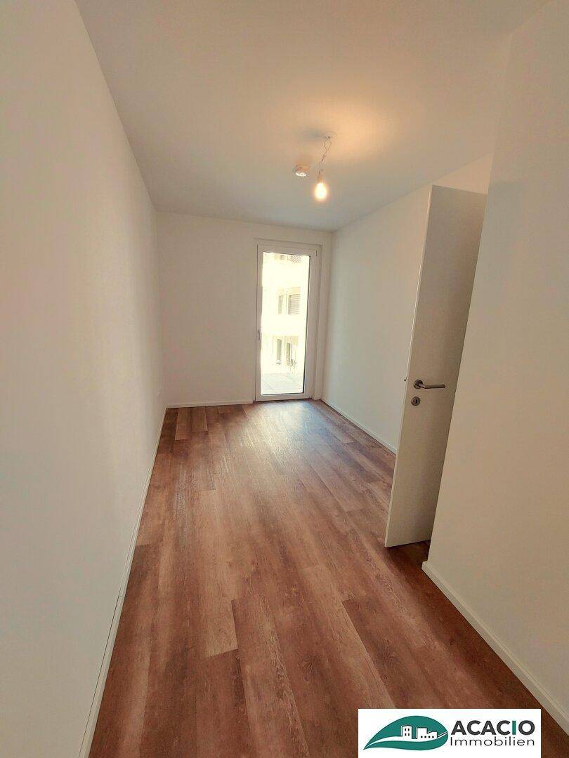 Helles Zimmer mit Laminatboden und Zugang zu einem Außenbereich, ideal als Schlaf- oder Arbeitszimmer.