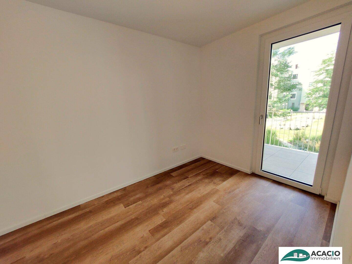 Gemütliches Schlafzimmer mit Laminatboden und direktem Zugang zum Balkon, hell und einladend.