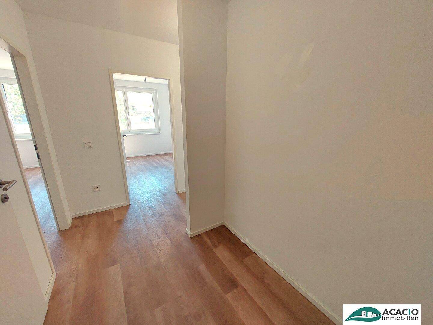 Heller Flur mit Laminatboden, der zu den verschiedenen Zimmern der Wohnung führt.