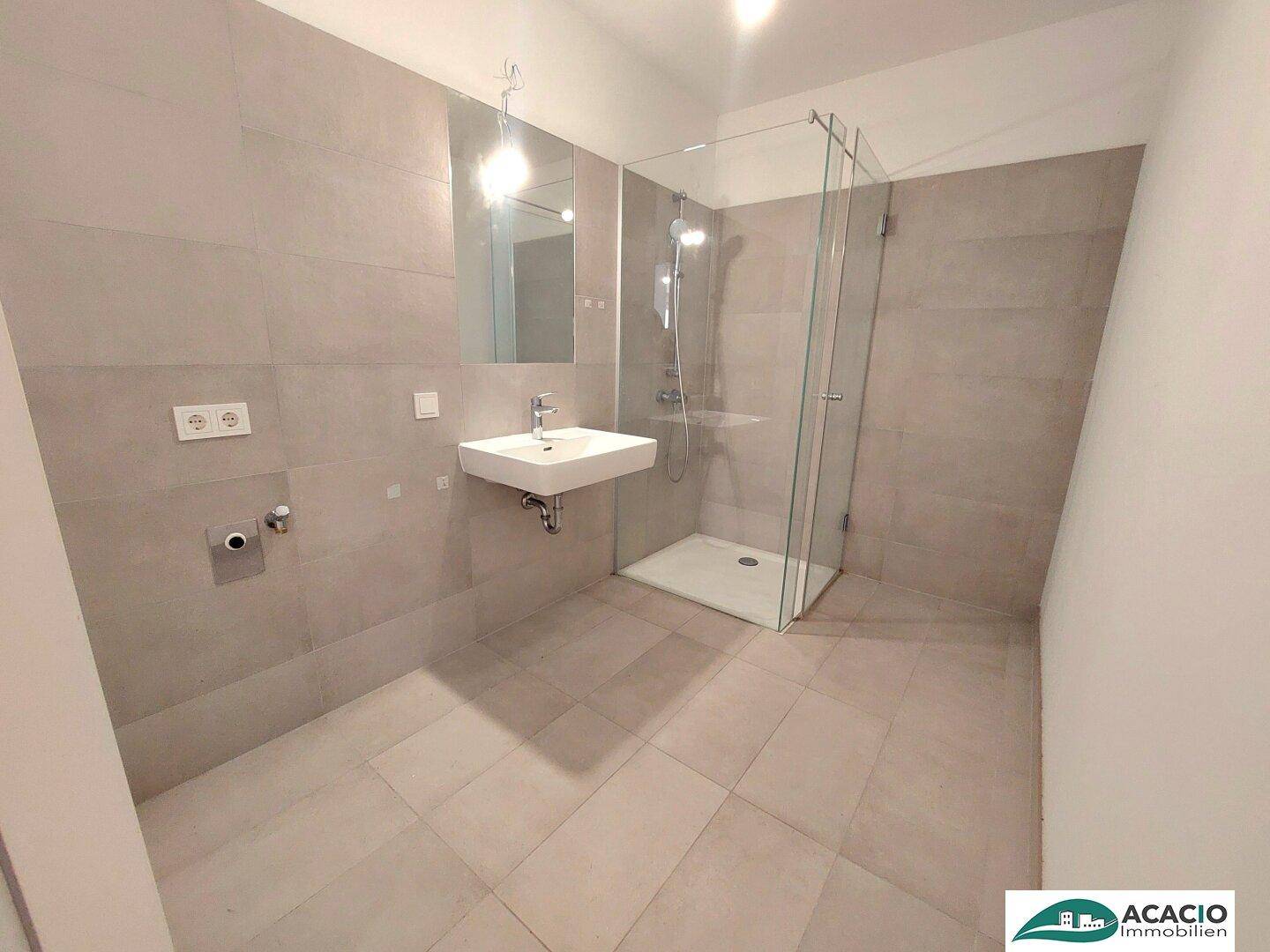Modernes Badezimmer mit ebenerdiger Dusche, Wand-WC und großformatigen Fliesen.