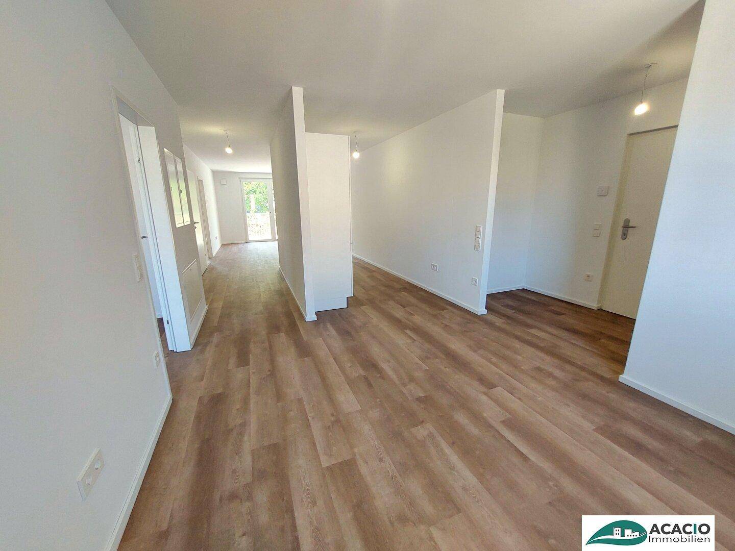 Heller Eingangsbereich, der sich offen in den Wohnbereich mit Laminatboden einfügt.