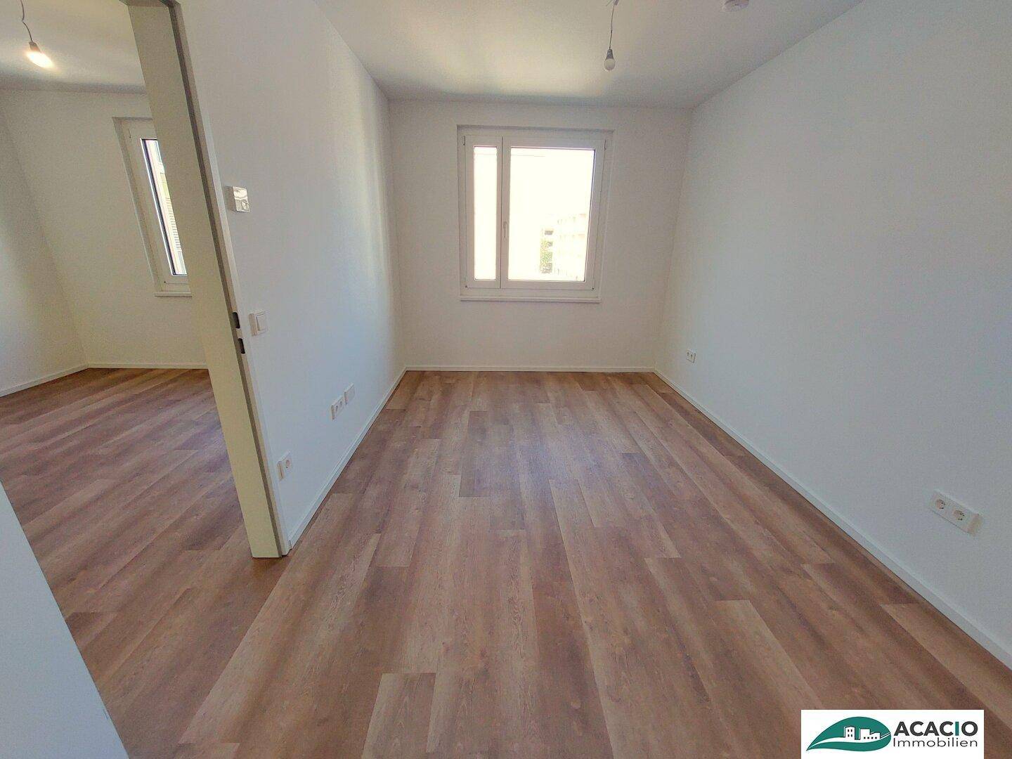 Helles Zimmer mit Laminatboden und weiß gestrichenen Wänden, bereit zur individuellen Gestaltung.