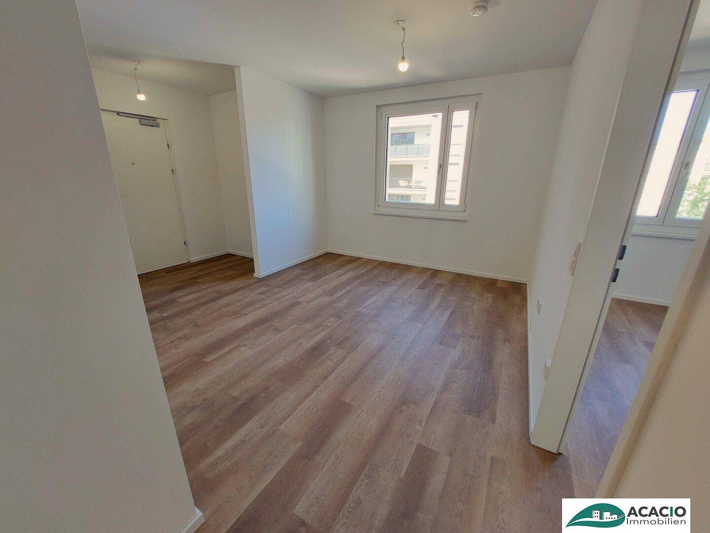Geräumiges Schlafzimmer mit Laminatboden und großen Fenstern, die viel Tageslicht hereinlassen.