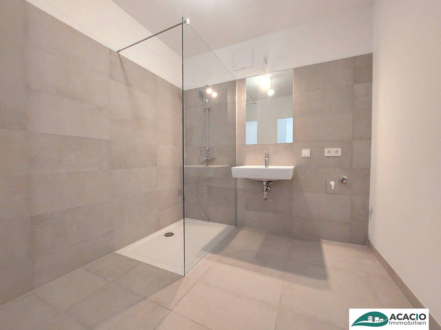 Modernes Badezimmer mit ebenerdiger Dusche, eleganten grauen Fliesen und minimalistischem Waschbecken.