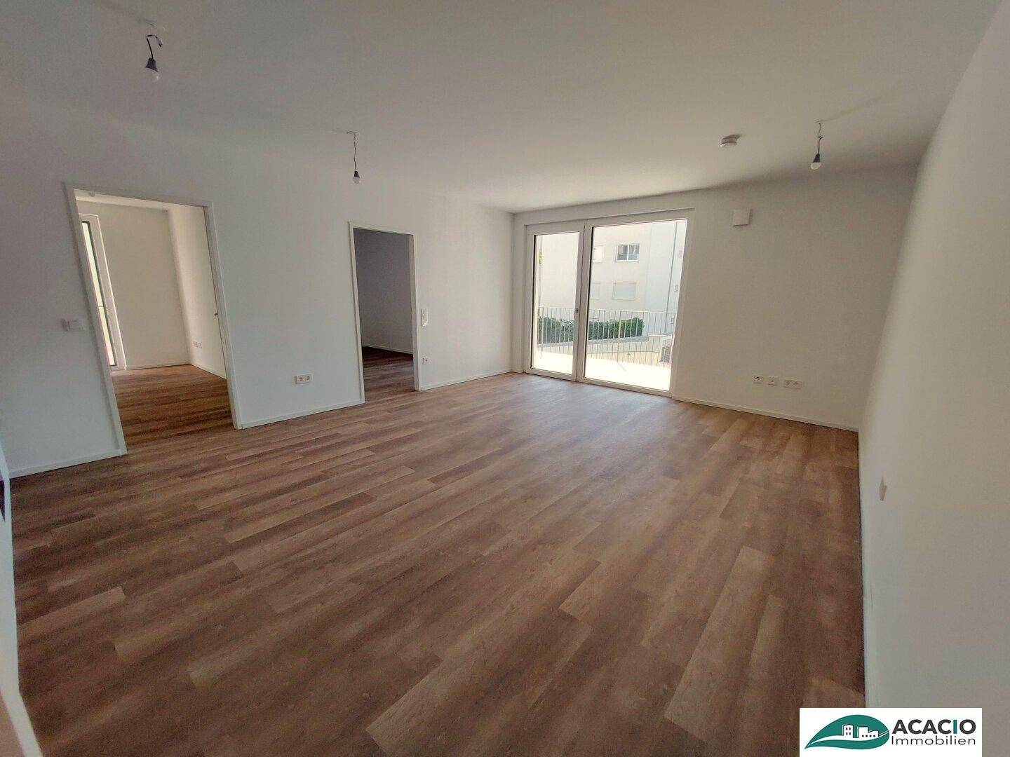 Heller Wohnbereich mit Zugang zur Loggia und Vinylboden in Holzoptik.