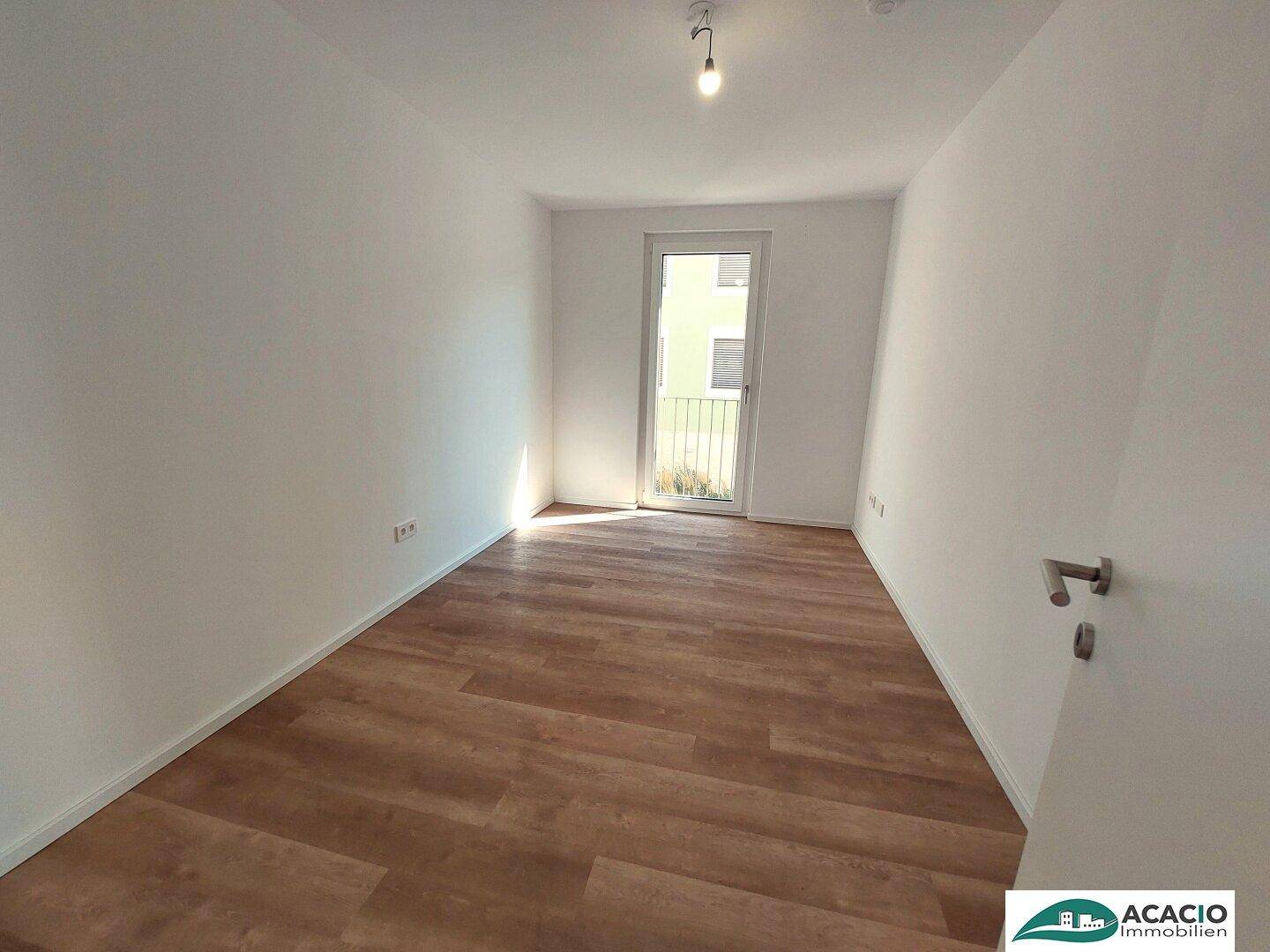 Helles Schlafzimmer mit Vinylboden und Zugang zu einem französischen Balkon.