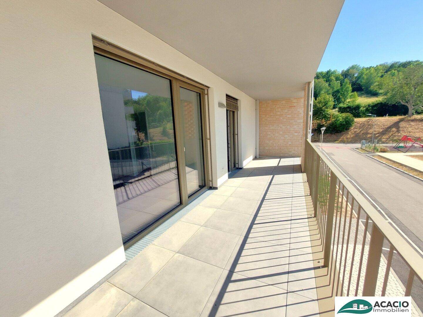 Sonnige Loggia mit Fliesenboden und Blick ins Grüne.