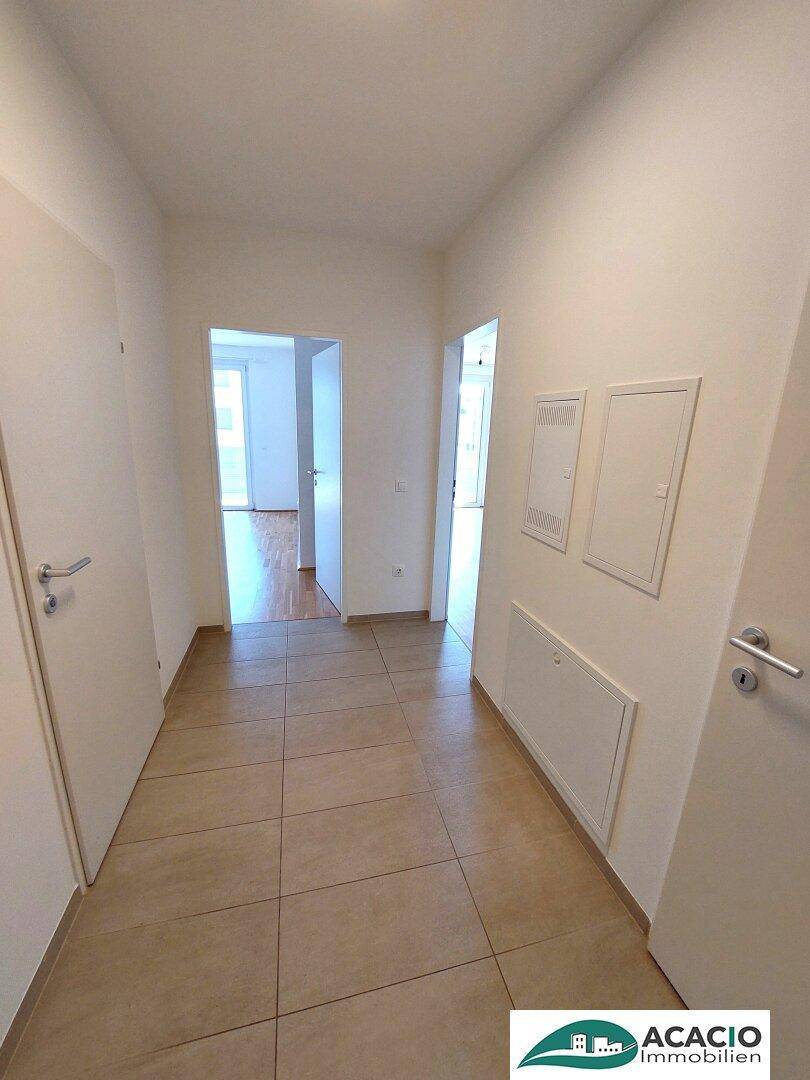 Heller Flur mit Fliesenboden und Zugang zu verschiedenen Zimmern der Wohnung.