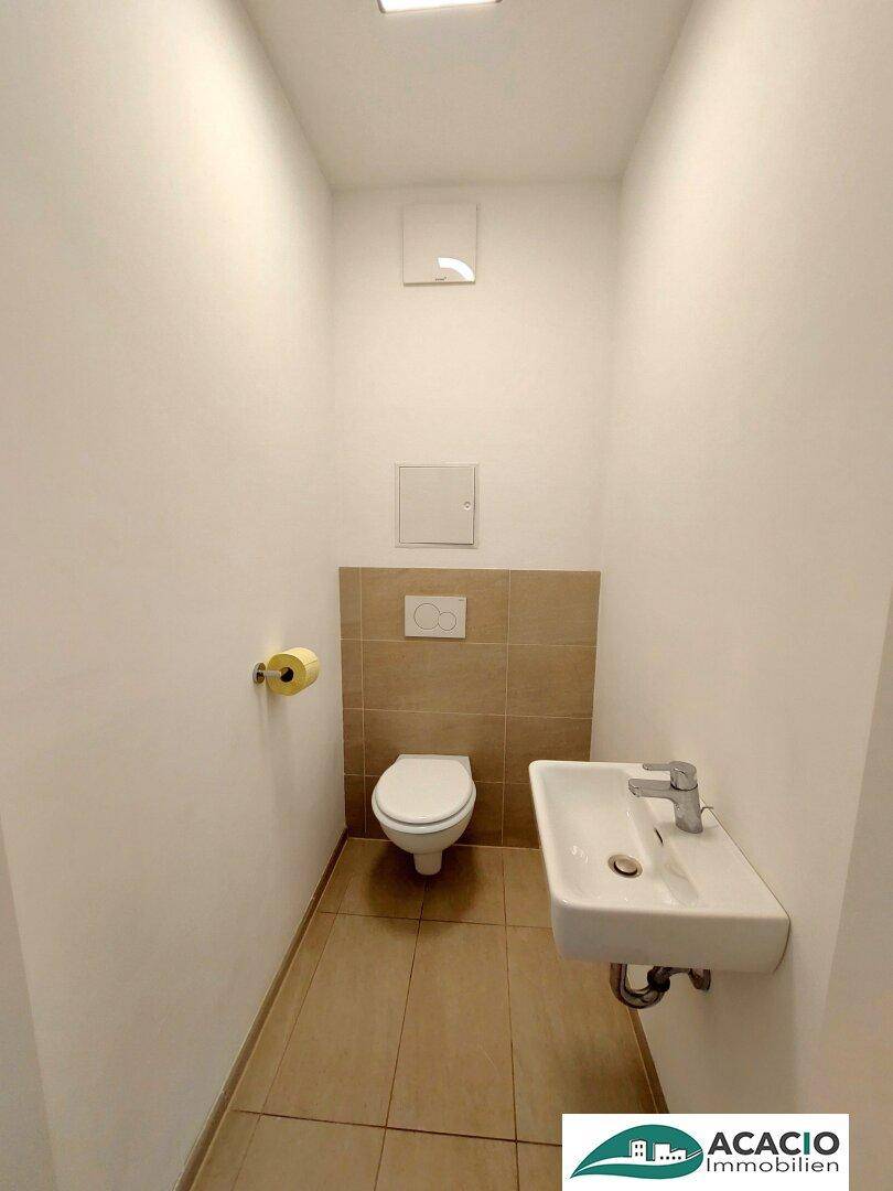 Separates WC mit Wand-WC und kleinem Waschbecken, praktisch für Gäste.