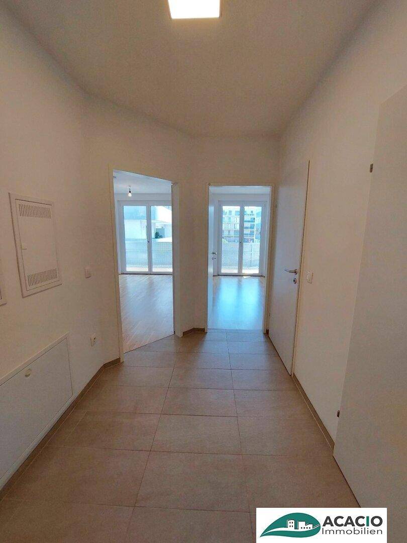 Geräumiger Flur mit hellen Fliesen und Zugang zu verschiedenen Zimmern der Wohnung.