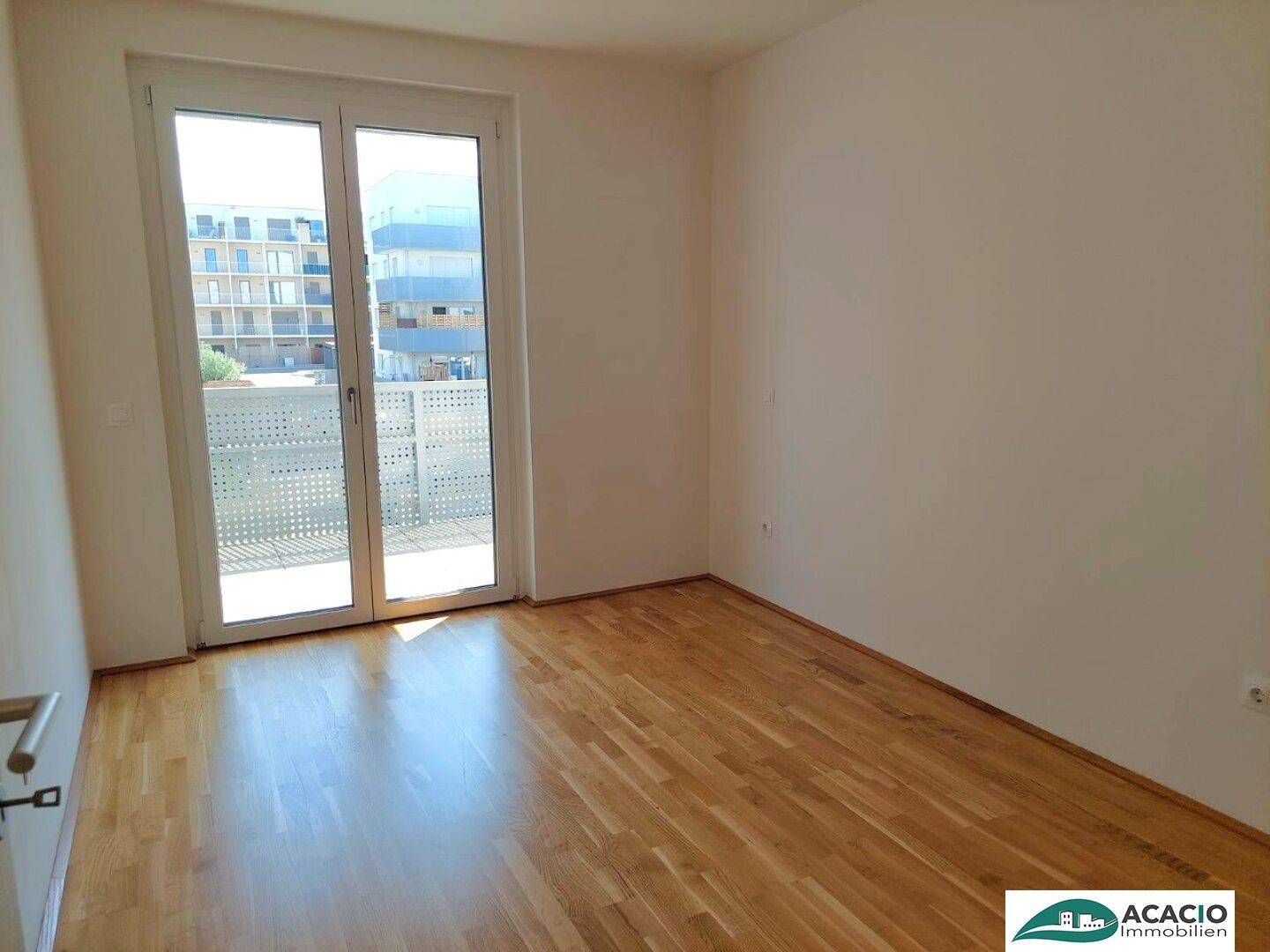 Helles Schlafzimmer mit Parkettboden und direktem Zugang zu einem sonnigen Balkon.