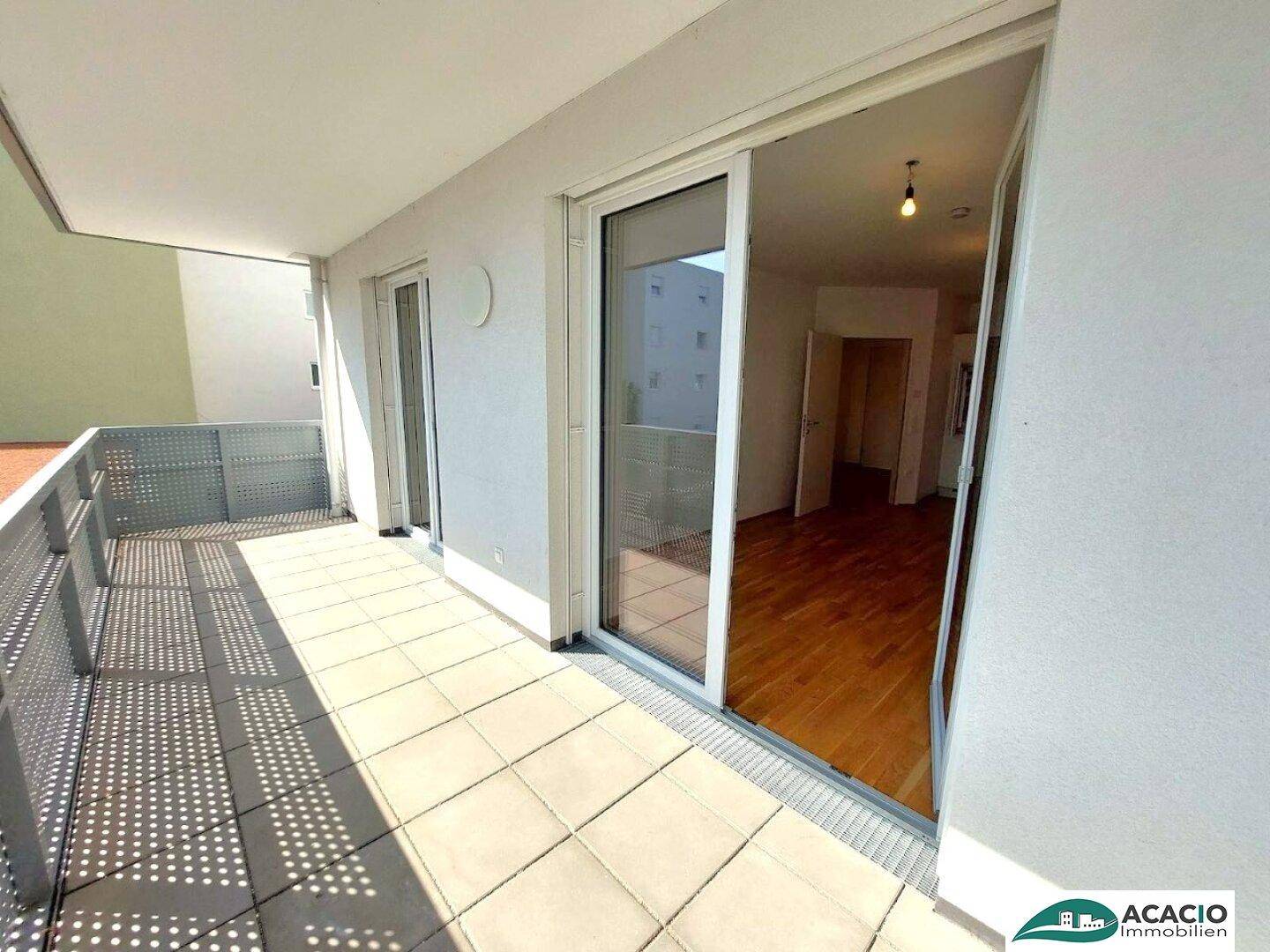 Heller Balkon mit Zugang vom Innenbereich und Blick auf die Umgebung.