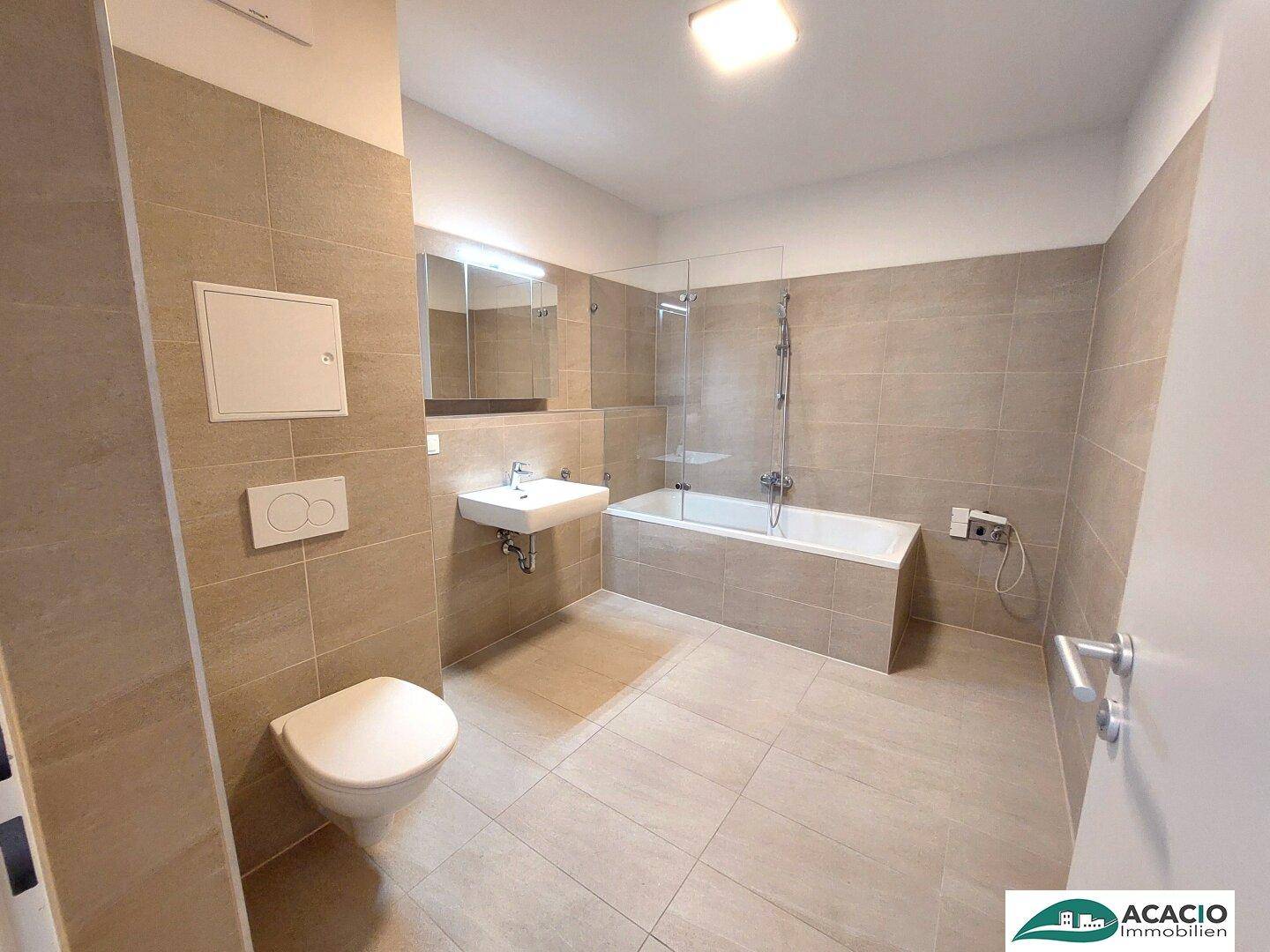 Modernes Badezimmer mit beigefarbenen Fliesen, Badewanne und wandhängendem WC.