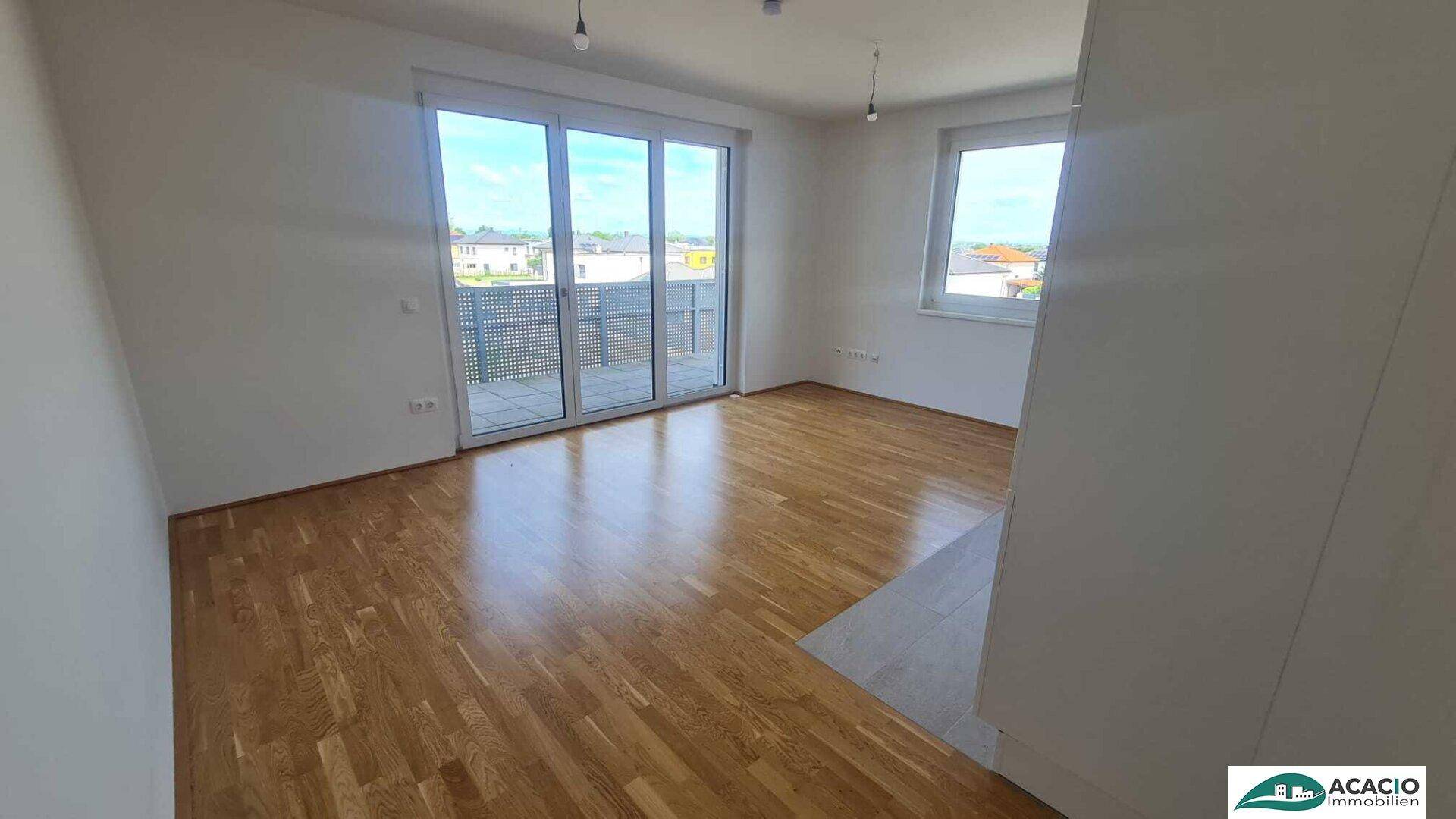 Geräumiger Wohnbereich mit hellem Parkettboden und direktem Zugang zum sonnigen Balkon.