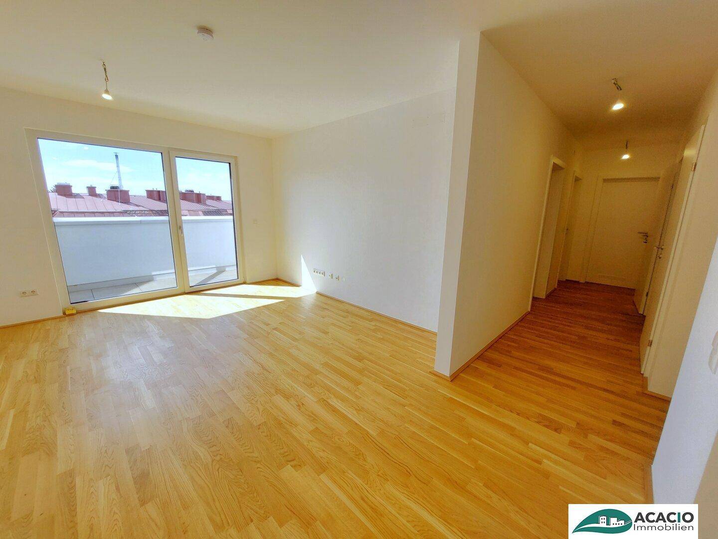 Geräumiges Zimmer mit Holzboden und viel Tageslicht durch die große Terrassentür.