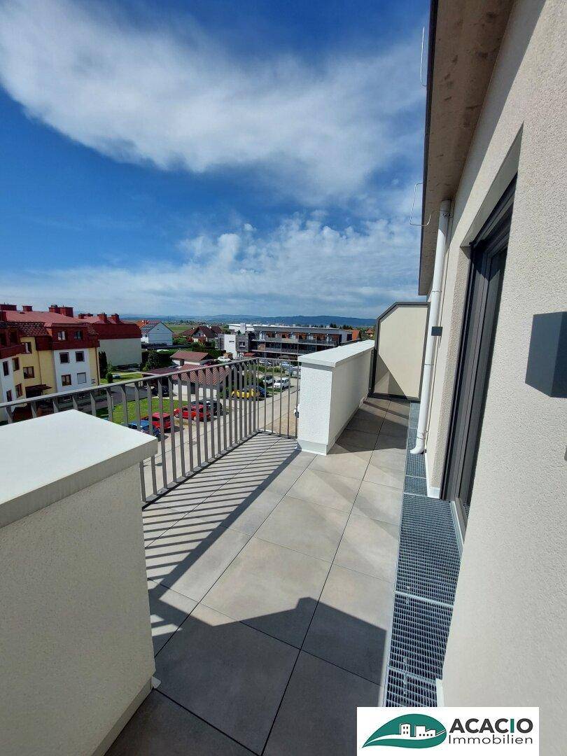 Geräumiger Balkon mit Fliesenboden und Blick auf die Umgebung.
