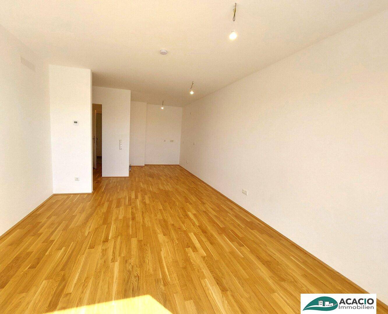 Leerer Raum mit Holzboden und weißen Wänden, bereit zur individuellen Gestaltung.