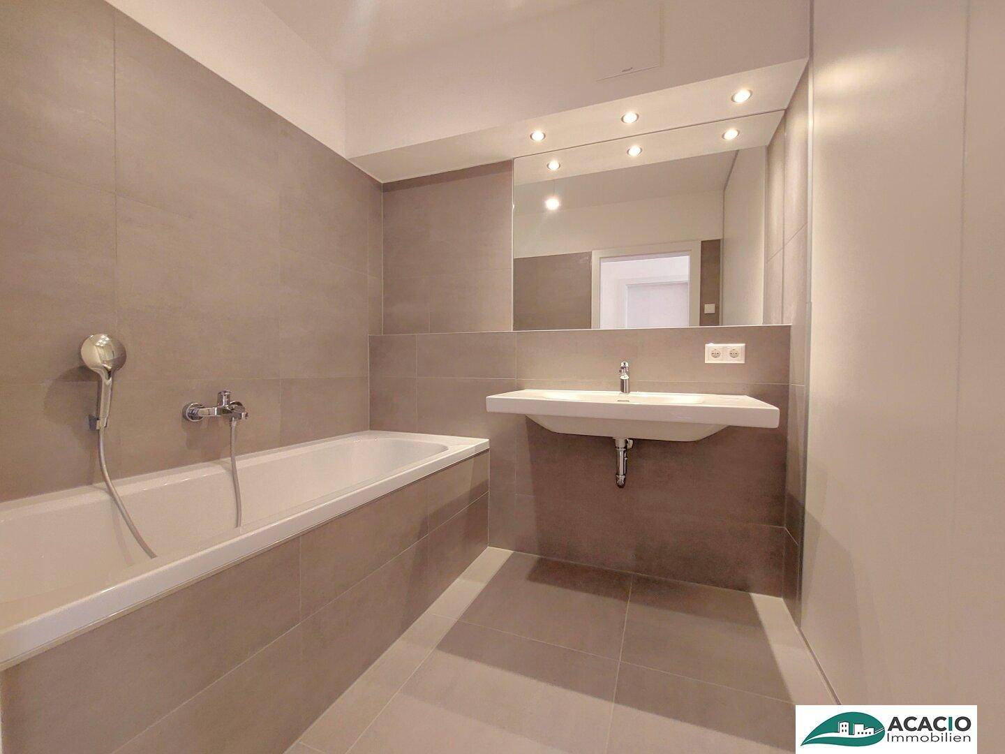 Modernes Badezimmer mit Badewanne, Waschbecken und großem Spiegel.