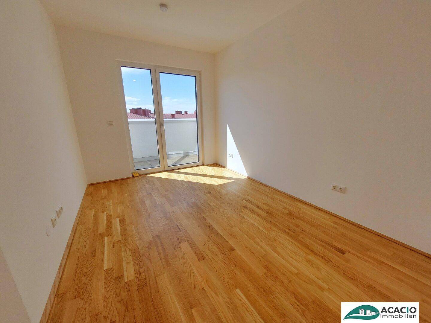 Lichtdurchflutetes Zimmer mit Holzboden und direktem Zugang zur Terrasse.