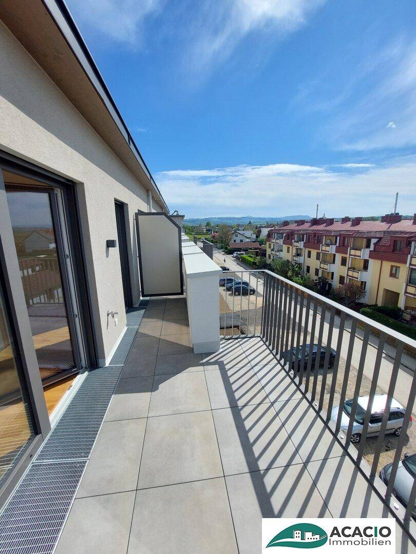 Langer Balkon mit Fliesenboden und Blick auf die umliegende Wohngegend.