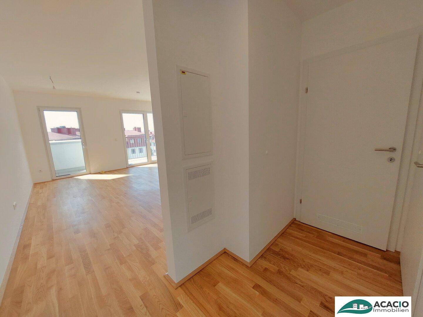 Heller Flur mit Holzparkettboden, der in den offenen Wohnbereich führt.